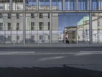 a large building is reflected in the side of the street that goes along this narrow road