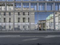 a large building is reflected in the side of the street that goes along this narrow road