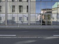 a large building is reflected in the side of the street that goes along this narrow road