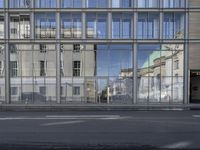 a large building is reflected in the side of the street that goes along this narrow road