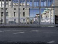 a large building is reflected in the side of the street that goes along this narrow road