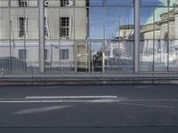 a large building is reflected in the side of the street that goes along this narrow road