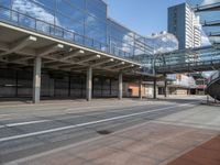 an empty street in front of some large buildings and the train on one side has a glass balcony above it