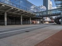 an empty street in front of some large buildings and the train on one side has a glass balcony above it