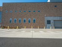 empty parking lot with empty parking space in front of building with several windows and metal poles