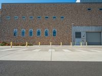 empty parking lot with empty parking space in front of building with several windows and metal poles