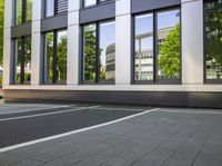 an empty street in front of the window of a tall building on a sunny day