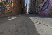 the view of a very narrow alley with grafitti on it as a blurry camera lens and a building on one side