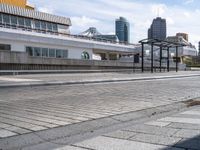 the empty brick walkway is by the water next to the train station and buildings in a city