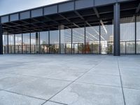 the exterior of a modern building with glass walls and a concrete slab floor below it