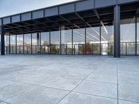 the exterior of a modern building with glass walls and a concrete slab floor below it