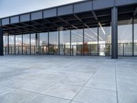 the exterior of a modern building with glass walls and a concrete slab floor below it