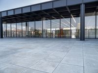 the exterior of a modern building with glass walls and a concrete slab floor below it