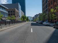 an empty street with buildings and parked cars on the sidewalks and green lanes on the sidewalk