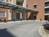 a building with a parking area next to it with a stone walkway and a carportion