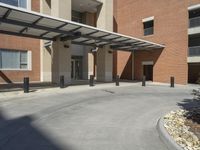 a building with a parking area next to it with a stone walkway and a carportion