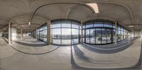 a panoramic view of an empty lobby from inside the building while some people sit