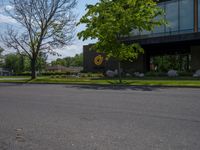 a building with a logo painted on the side near a street that has a sidewalk next to it