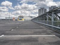 a paved parking lot with a small white building in the background of a large, gray city with a parking area in front of it