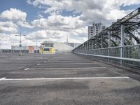 a paved parking lot with a small white building in the background of a large, gray city with a parking area in front of it