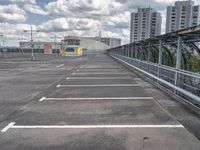 a paved parking lot with a small white building in the background of a large, gray city with a parking area in front of it