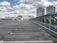 a paved parking lot with a small white building in the background of a large, gray city with a parking area in front of it