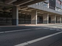 the empty streets have a large building above them with some windows on them, and some people are walking