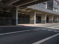 the empty streets have a large building above them with some windows on them, and some people are walking