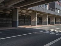 the empty streets have a large building above them with some windows on them, and some people are walking