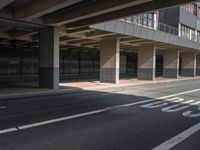 the empty streets have a large building above them with some windows on them, and some people are walking