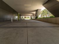 a modern concrete building has a long and wide sidewalk with grey cement floors and an arched roof