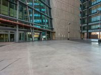 a skateboarder doing tricks on the sidewalk in front of a very tall building