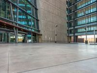 a skateboarder doing tricks on the sidewalk in front of a very tall building