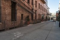 a brick building with an iron railing next to a sidewalk that leads into a building with brown brick walls