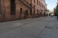 a brick building with an iron railing next to a sidewalk that leads into a building with brown brick walls