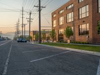 an empty street in front of a large red brick building on the other side of the road is a street light that has a line for motorists