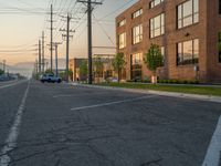 an empty street in front of a large red brick building on the other side of the road is a street light that has a line for motorists