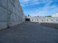 the empty parking lot in front of a wall with apartment buildings on it and a skateboarder on a ramp