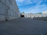 the empty parking lot in front of a wall with apartment buildings on it and a skateboarder on a ramp