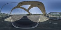 a fish eye lens shot shows the highway in the foreground and an arched bridge with arches over it