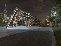 an open structure with city lights in the distance and a building on each side and two trees,