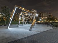 an open structure with city lights in the distance and a building on each side and two trees,