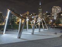 an open structure with city lights in the distance and a building on each side and two trees,