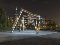 an open structure with city lights in the distance and a building on each side and two trees,