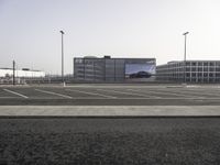 an empty parking lot and cars waiting for the light to change on the road on the side walk