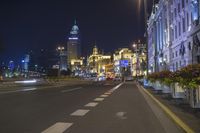 the street is empty during the evening time with lights on and buildings all around it