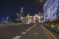 the street is empty during the evening time with lights on and buildings all around it