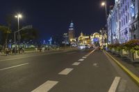 the street is empty during the evening time with lights on and buildings all around it