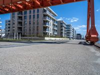 a long dock with concrete bricks beside a marina area with orange structures and buildings on the other side