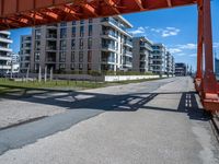 a long dock with concrete bricks beside a marina area with orange structures and buildings on the other side